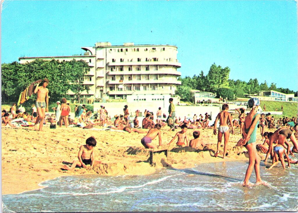 Carte poștală color: copii jucându-se la malul mării, cu hotelul Belona în spate