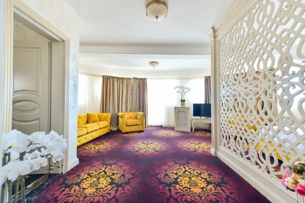 Livingul apartamentului de la Hotel Belona, cu canapele galbene și paravan alb traforat