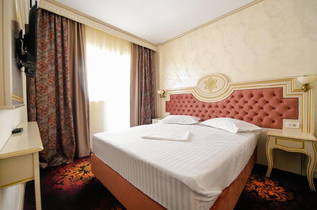 Cameră dublă la Hotel Belona, cu pat matrimonial și tăblie roz capitonată