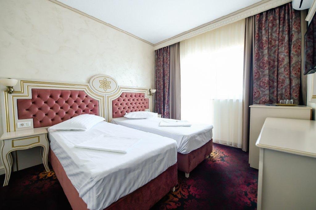 Cameră twin la Hotel Belona, cu două paturi și tăblii roz capitonate