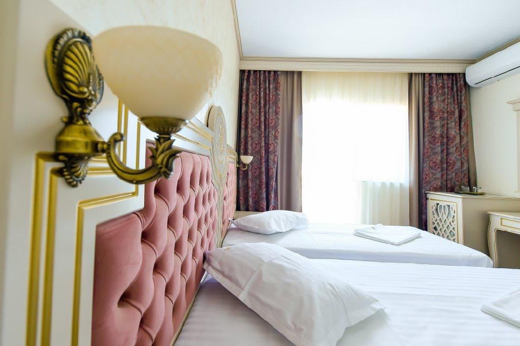 Detaliu dintr-o cameră de la Hotel Belona: aplică aurie și tăblie roz capitonată